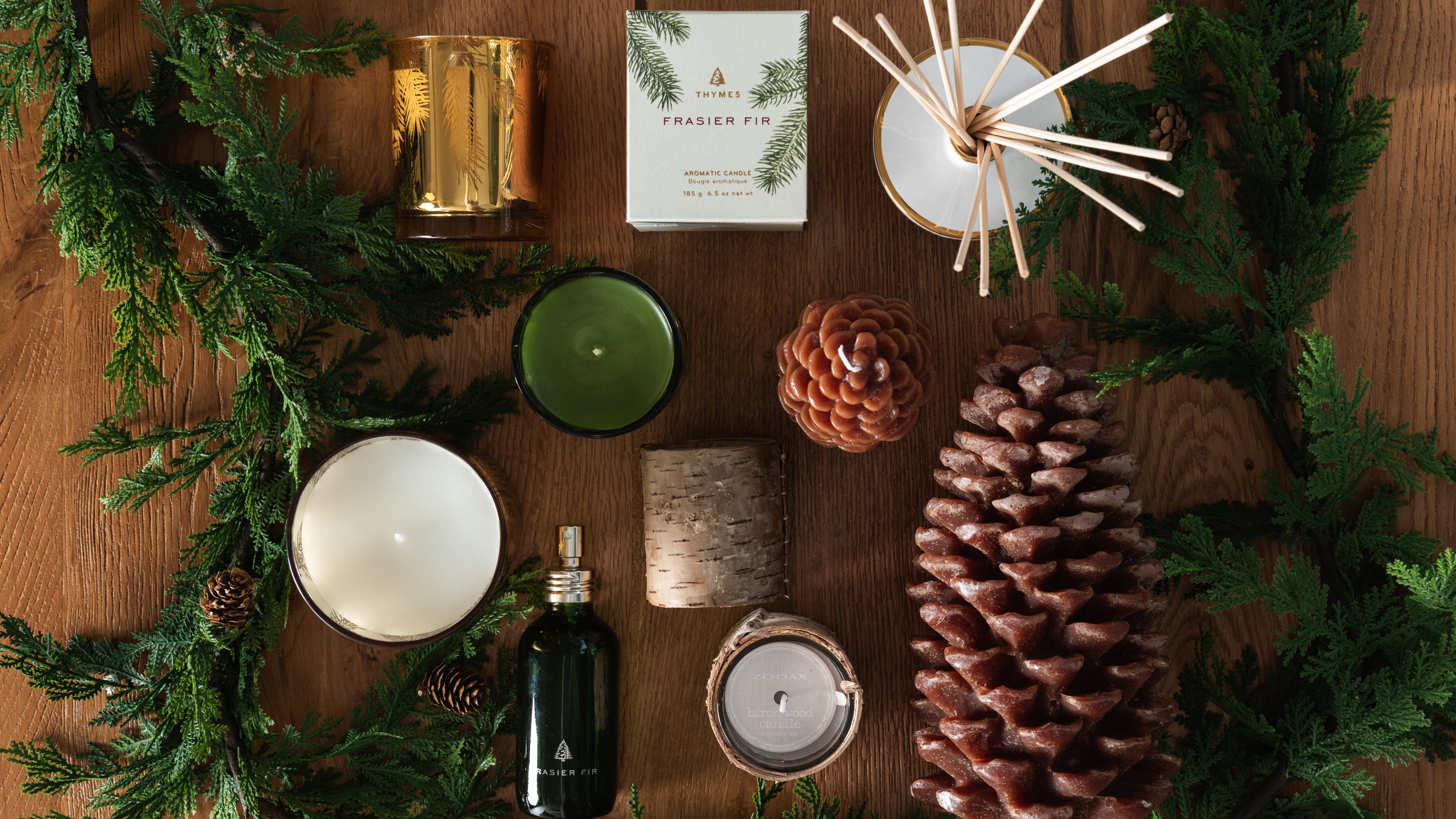 View from above of an assortment of seasonal candles on a wood table with garland at Addison West