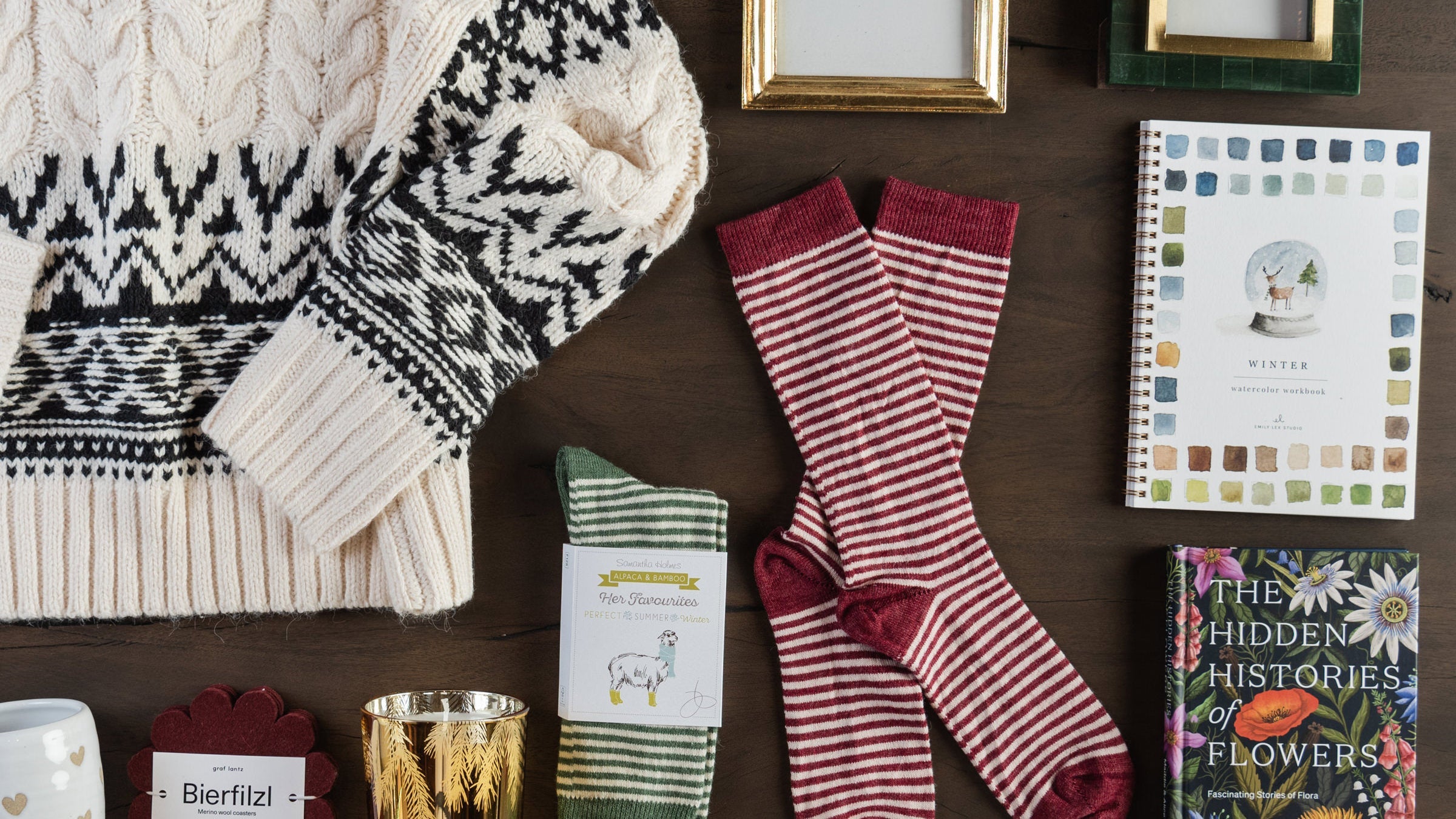 Gifts for her including picture frames, socks, watercolor workbook, books, candles, mugs and a sweater on a table at Addison West.