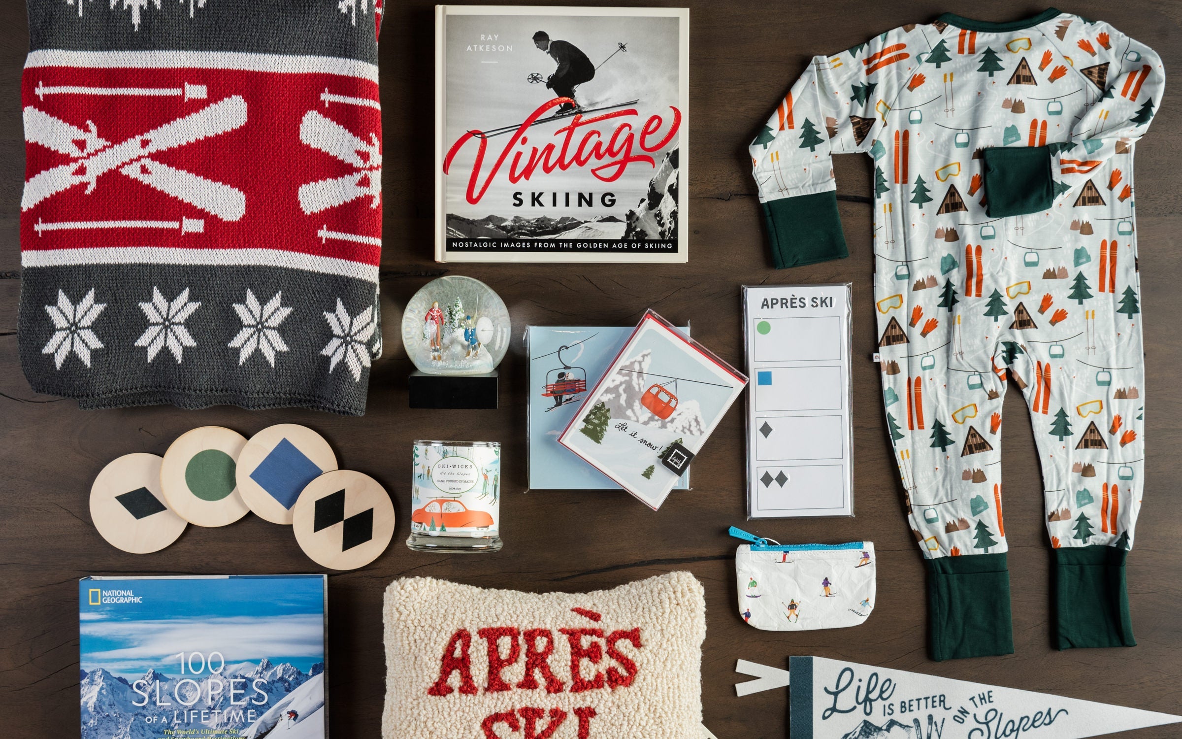 Collection of ski books, ski pillows, ski coasters, ski snow globe, ski pouches and more on a dark table at Addison West