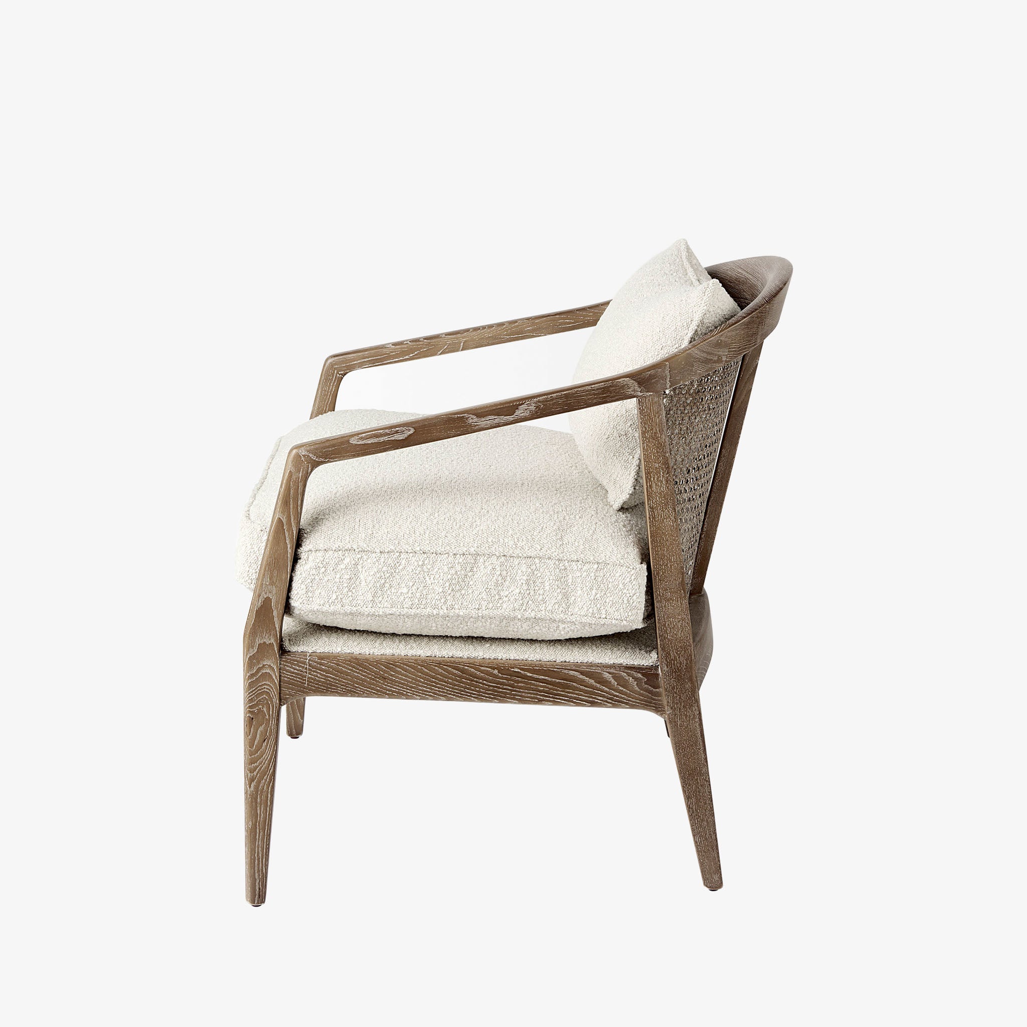 Armchair with light brown stain and sloped arms and cane back and light beige cushions on a white background