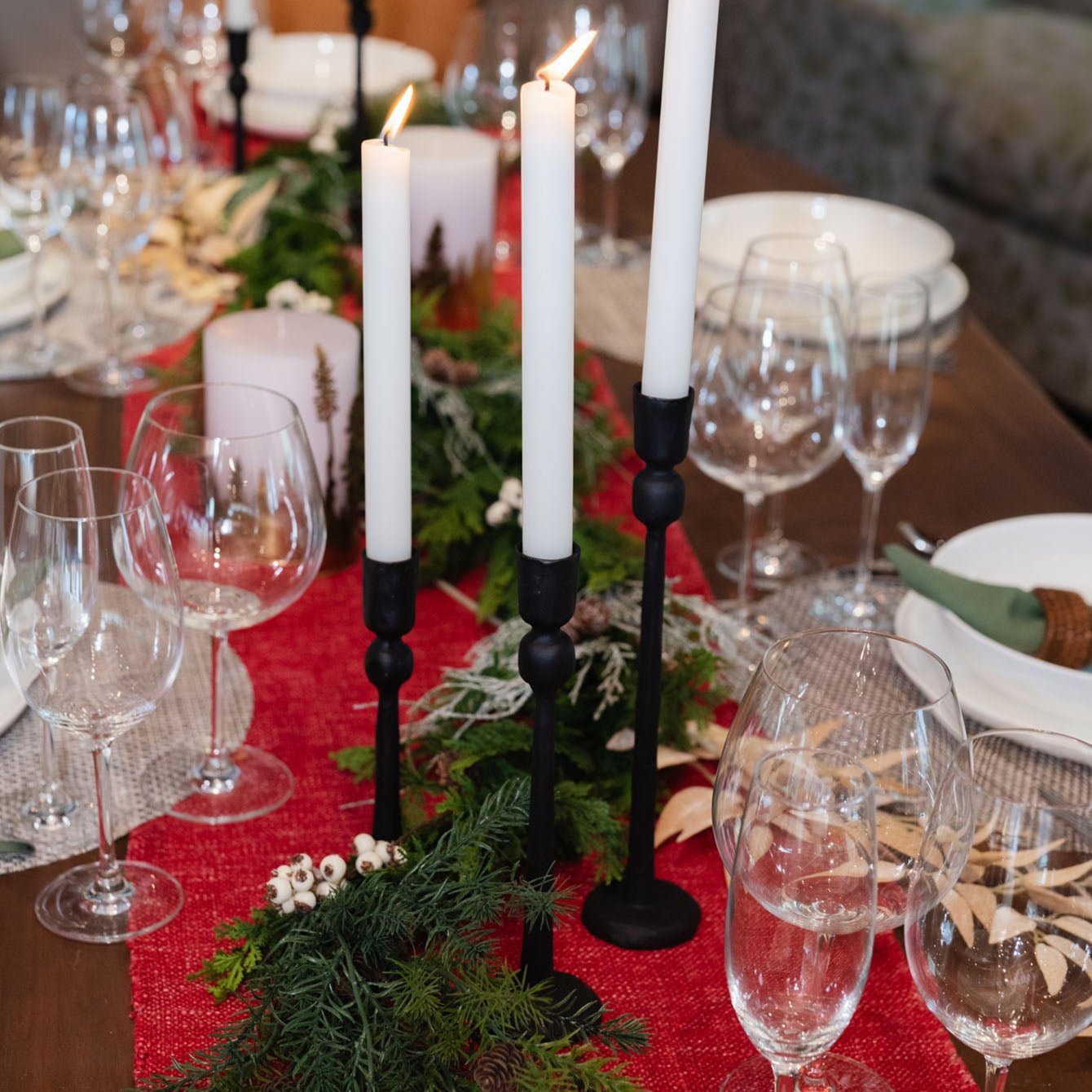 Dining table set with red holiday runner and black cast iron taper candle holders