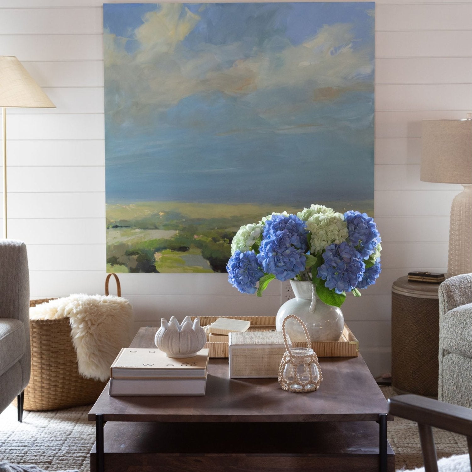 Coffee table with decorative items and white vase with twisted handles filled with hydrangea