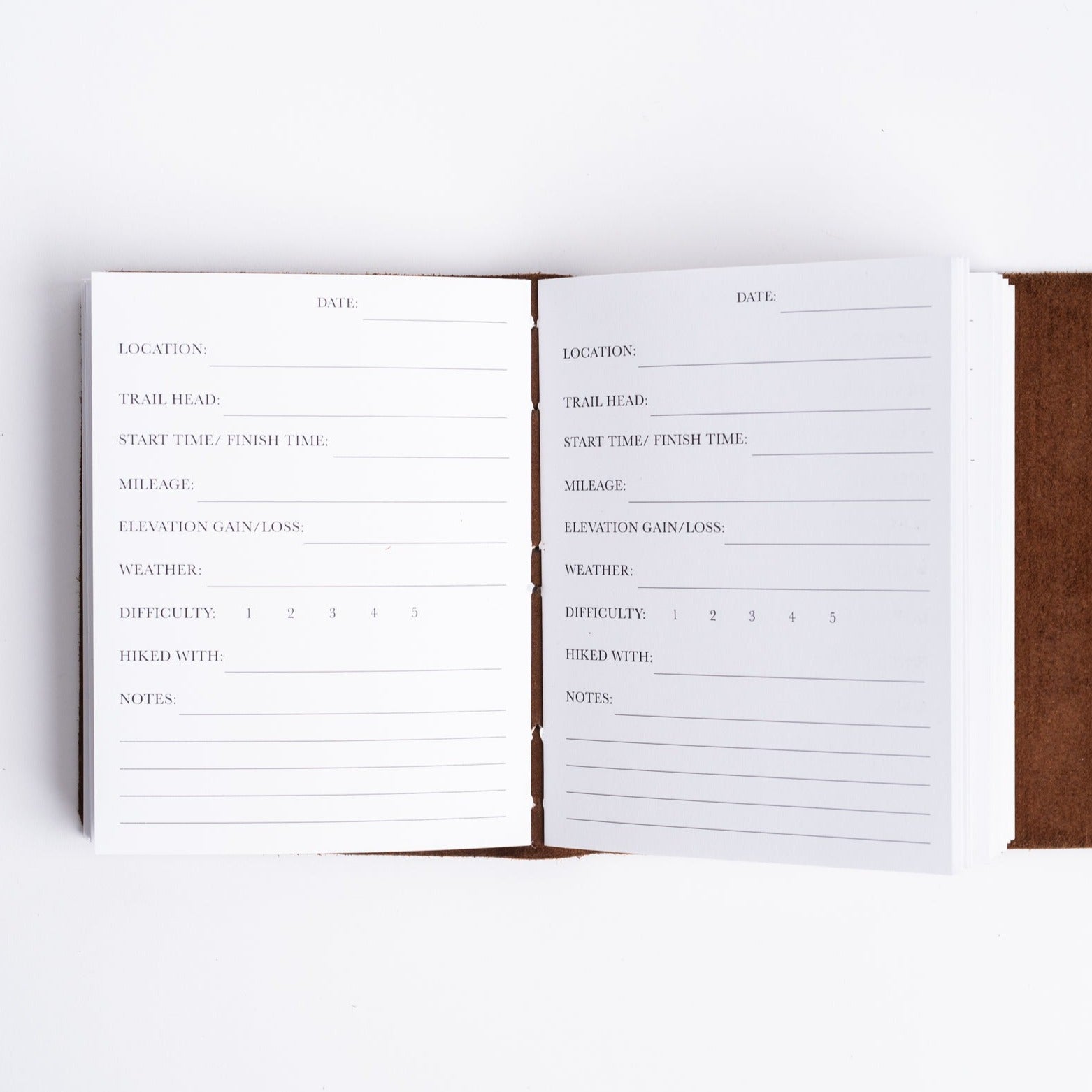 Handmade leather hiking journal from above with hiking log pages on white background