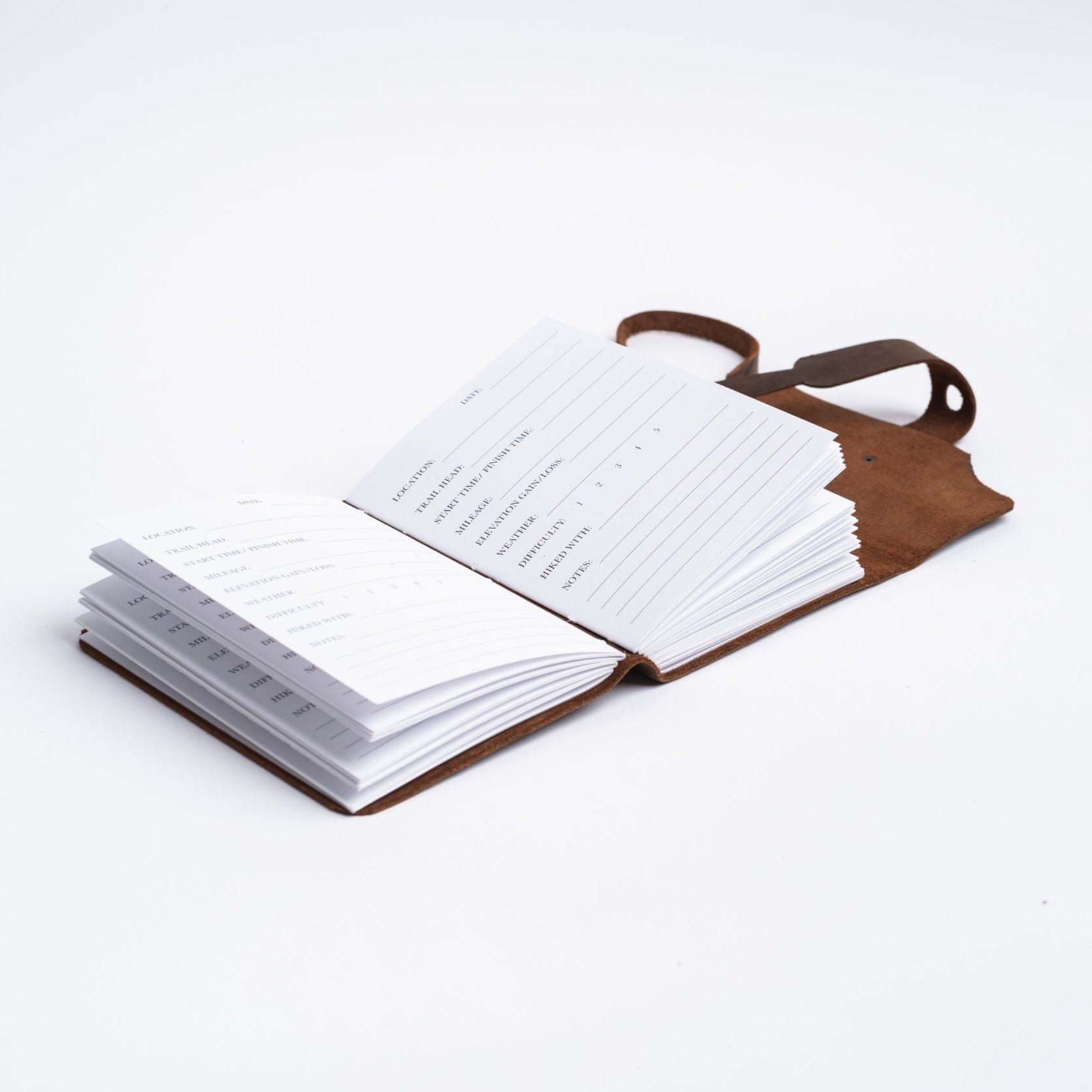 Handmade leather hiking journal from above with hiking log pages on white background