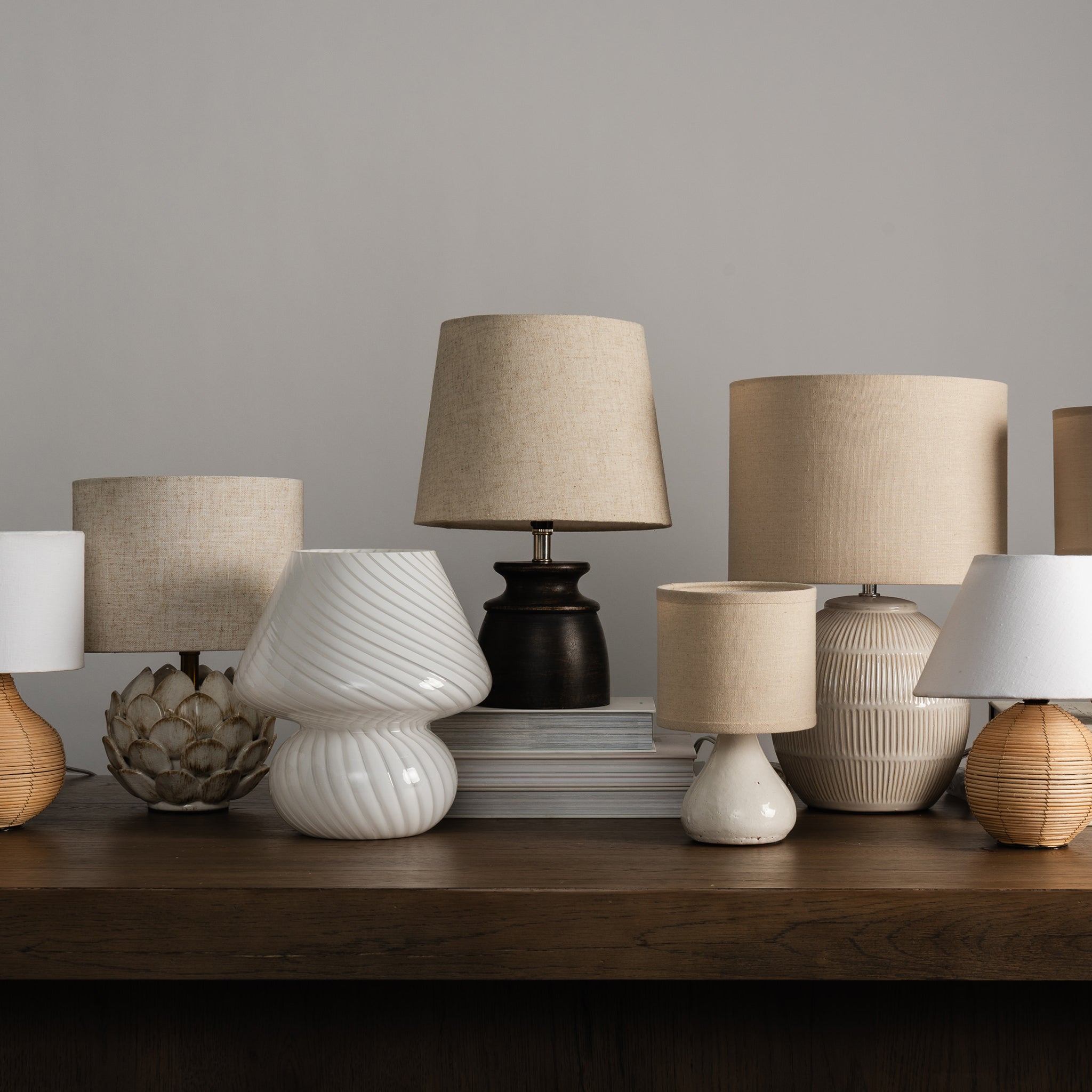 Collection of mini table lamps on a desk against a white background