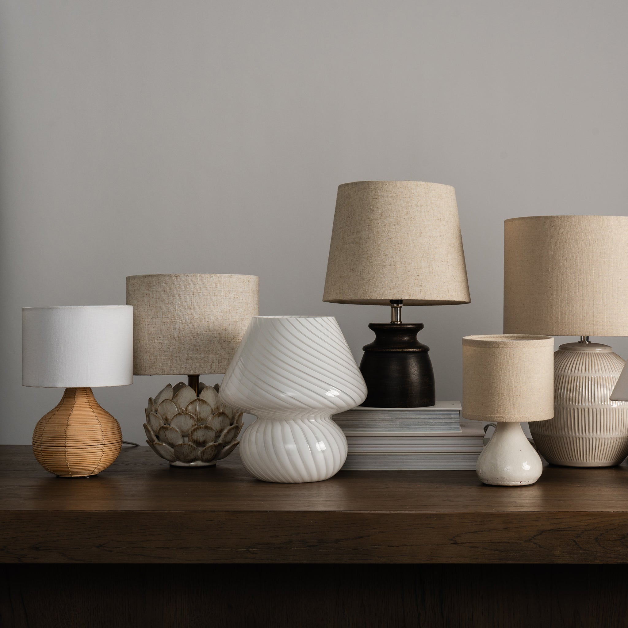 Collection of mini table lamps on a desk against a white background