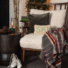 Ski & Snow Hand Hooked Pillow on a cozy chair in front of a holiday tree