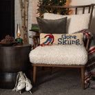 Gone Skiing Hand Hooked Pillow on a cozy chair in front of a holiday tree