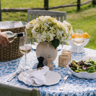 Small round white paper mache vase with handles on an outdoor table