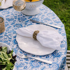 Beige linen napkin with seagrass braided napkin ring on an outdoor dining table