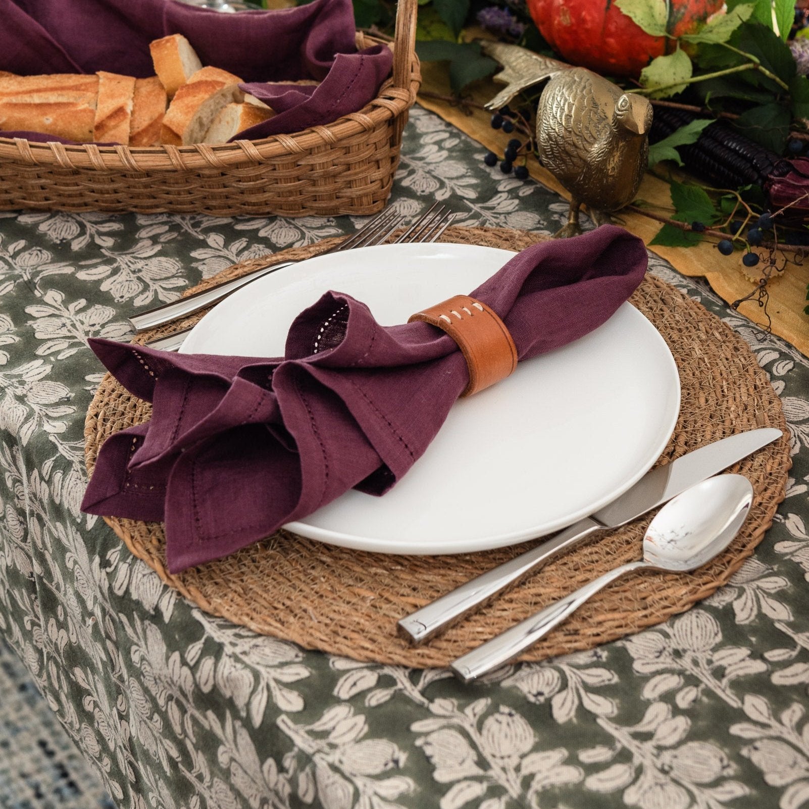 Linen Napkin in Plum with Leather Stitch Napkin Ring on a white plate on top of a Round Jute Placemat with Lucia Five Piece Place Setting on a festive fall table