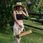 Hand Made in Vermont rattan harvest basket with handle being held by a woman in a field