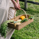 Hand Made in Vermont rattan harvest basket with handle being held by a woman in a field