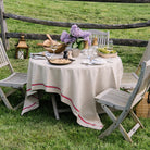 French Laundry Red Tablecloth 60" X 120" beige with red stripe on an outdoor dining table in a field