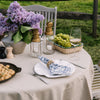 Beige linen napkin with seagrass braided napkin ring on an outdoor dining table