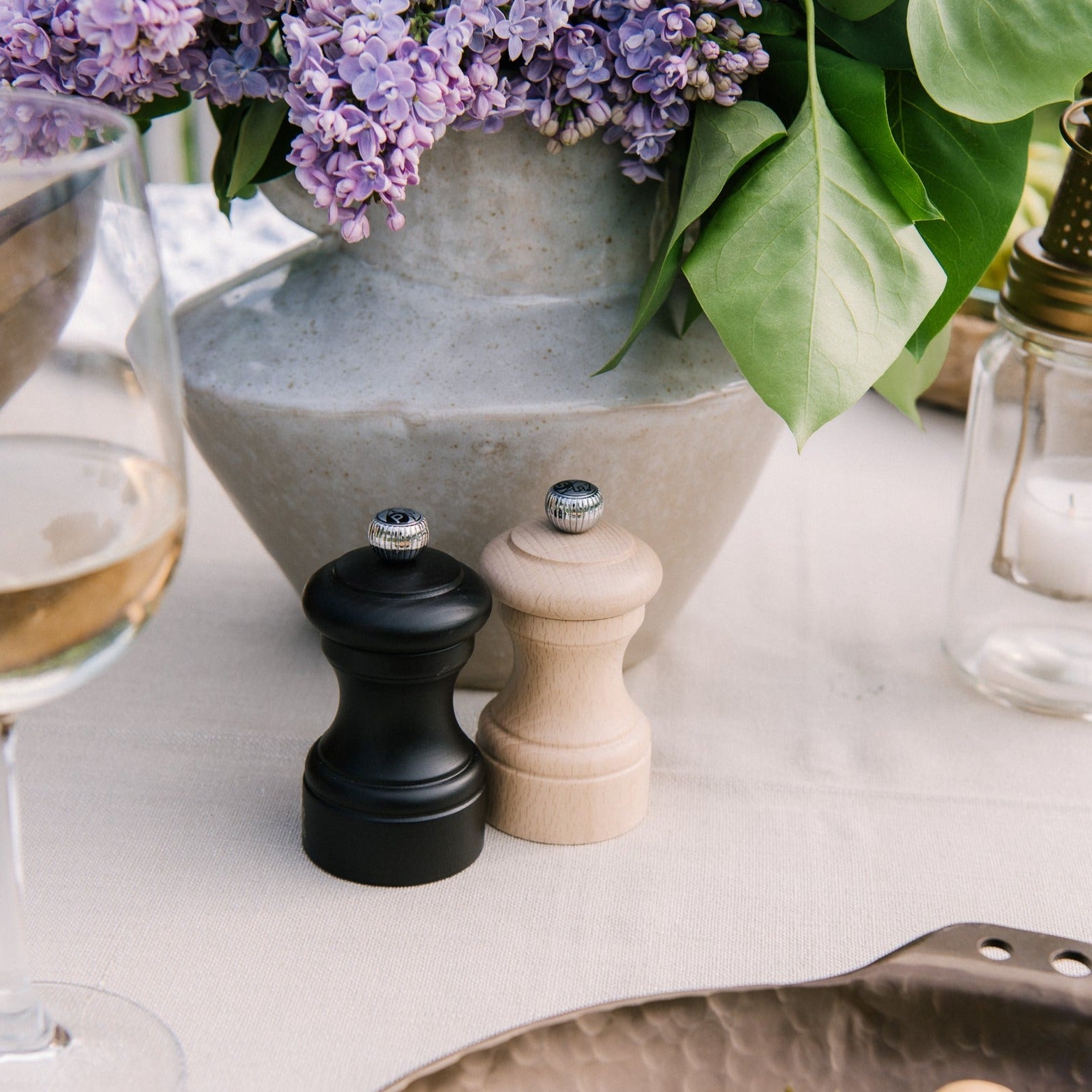 Peugeot Paris bistro salt and pepper mill set in natural and chocolate  on a table in front of a vase of flowers