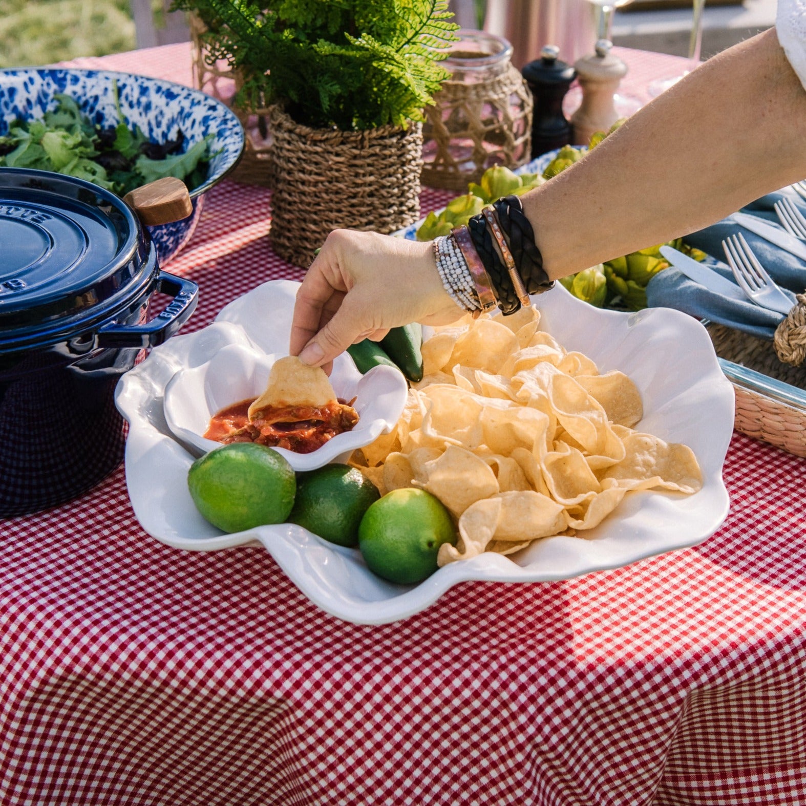 Beatriz Ball bloom chip and dip bowl filled with chips and a hand dipping a chip into salsa