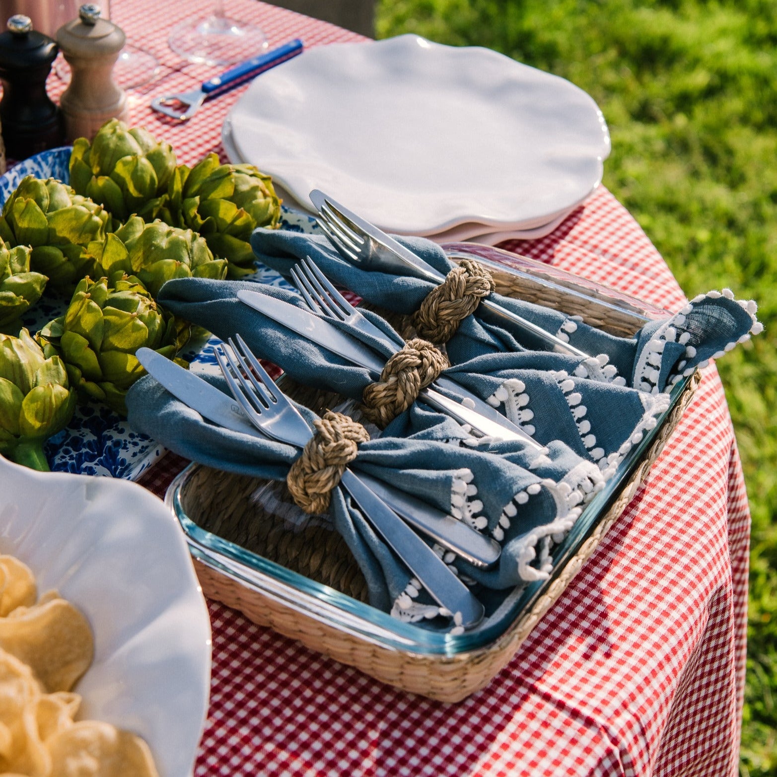 Blue linen napkin with seagrass braided napkin ring on an outdoor dining table