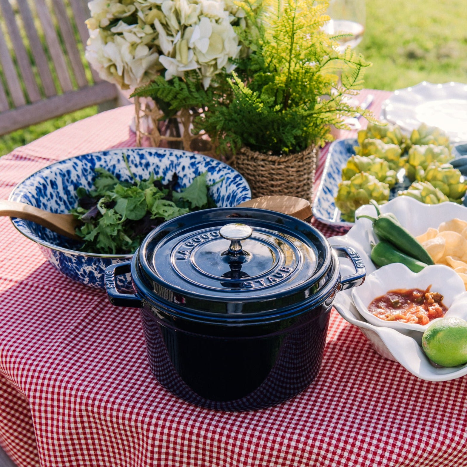 Blue Staub five quart cast iron dutch oven on an outdoor dining table