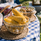 Three rattan wrapped glass bowls with food in them on an outdoor dining table