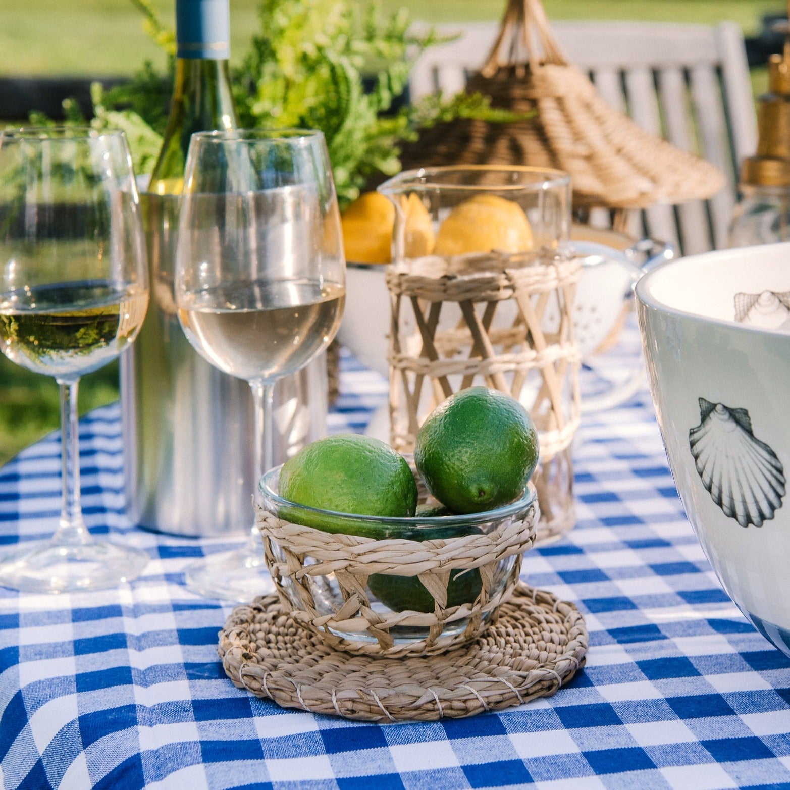 Three rattan wrapped glass bowl with limes in it on an outdoor dining table