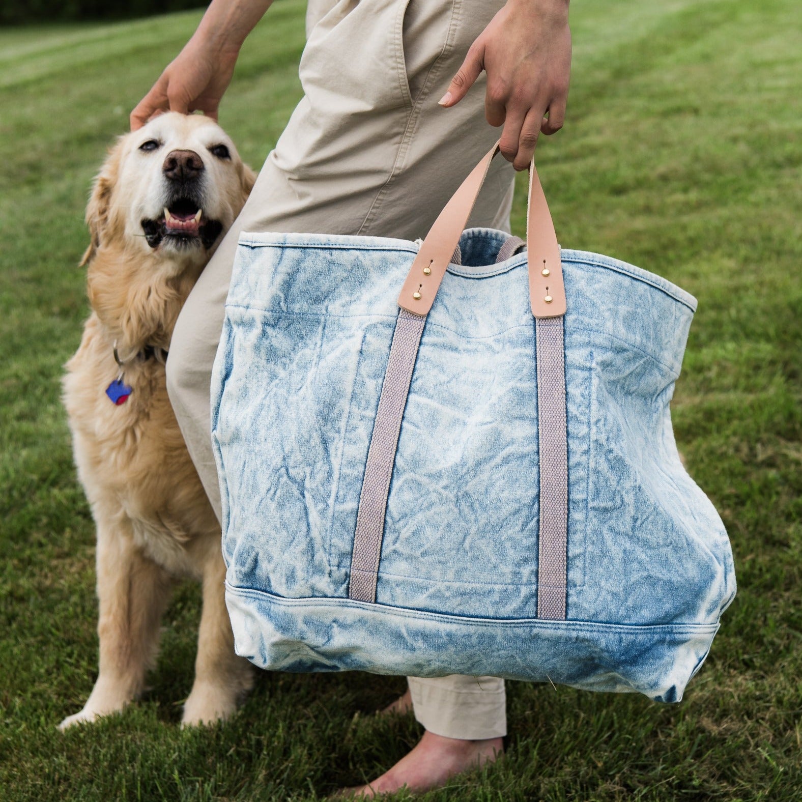 Immodest Cotton Large East-West Tote in Acid Wash with a woman holding it by the removable leather handle