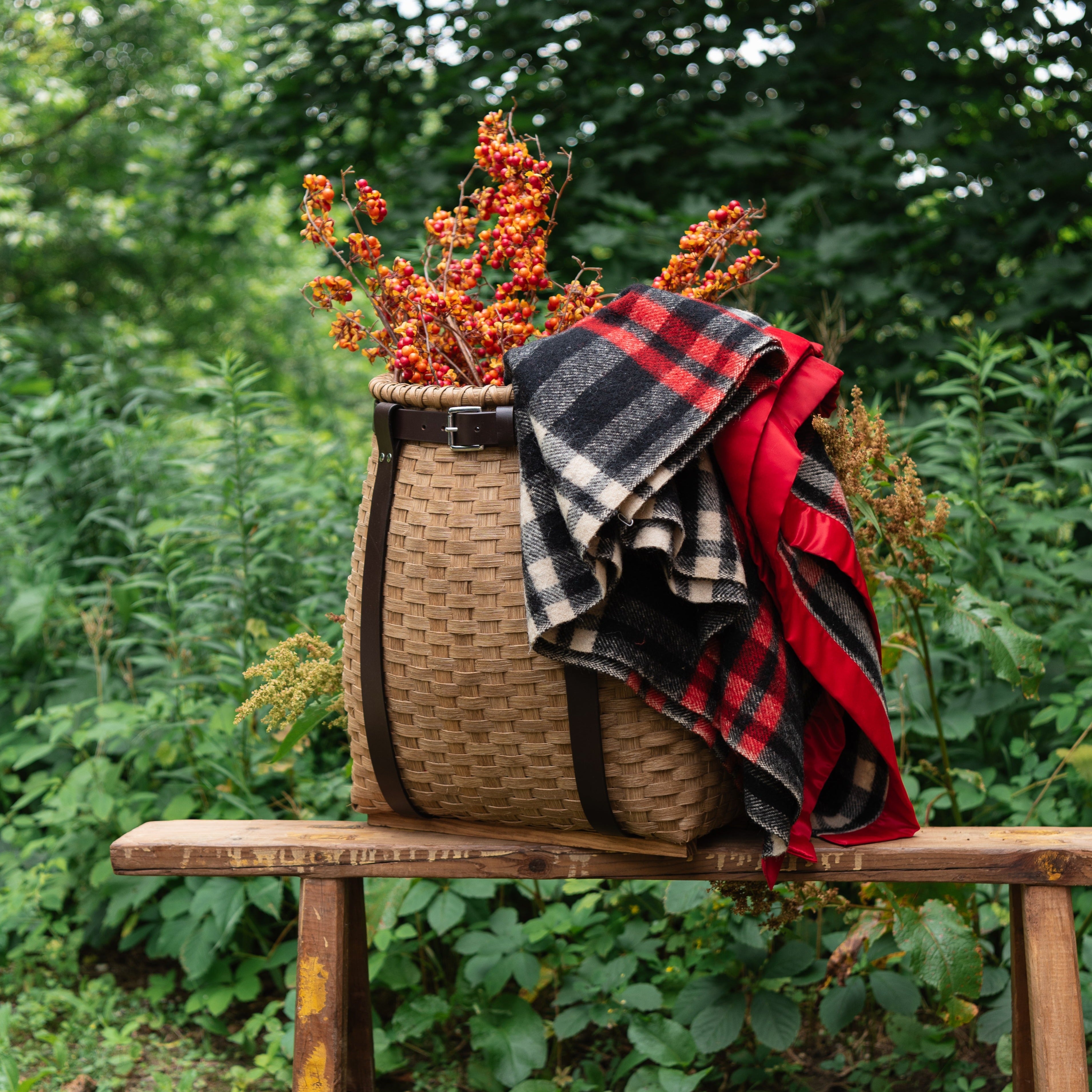 Handmade Vermont Pack Basket with a blanket and florals in front of a forest