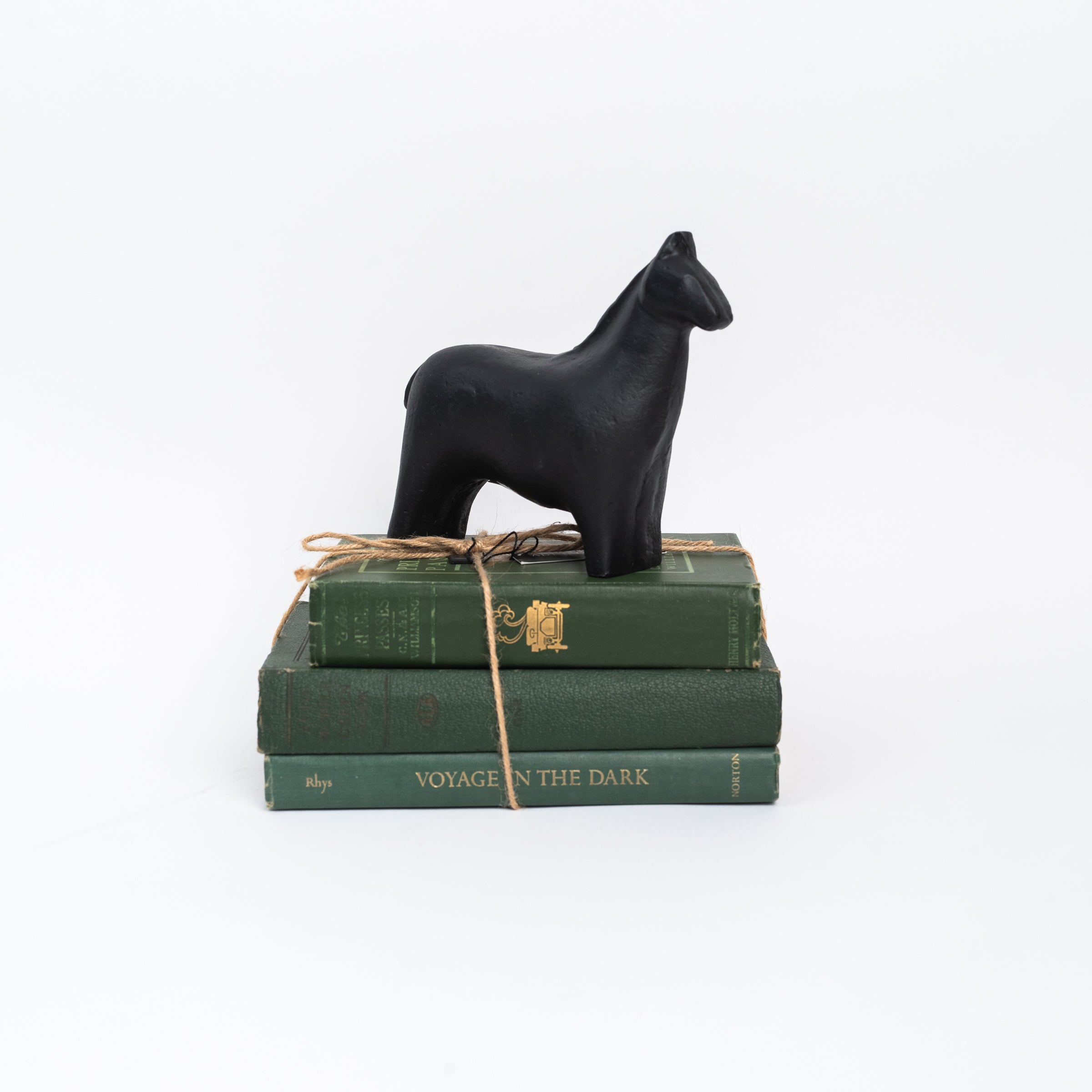 Horse Statue and a stack of green books on a white background