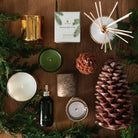 Birch wrapped candle, pine cone candle, and Thymes candles on a wood table with garland at Addison West