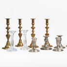 A group of brass glass pewter and silver candlesticks on a white background at Addison West