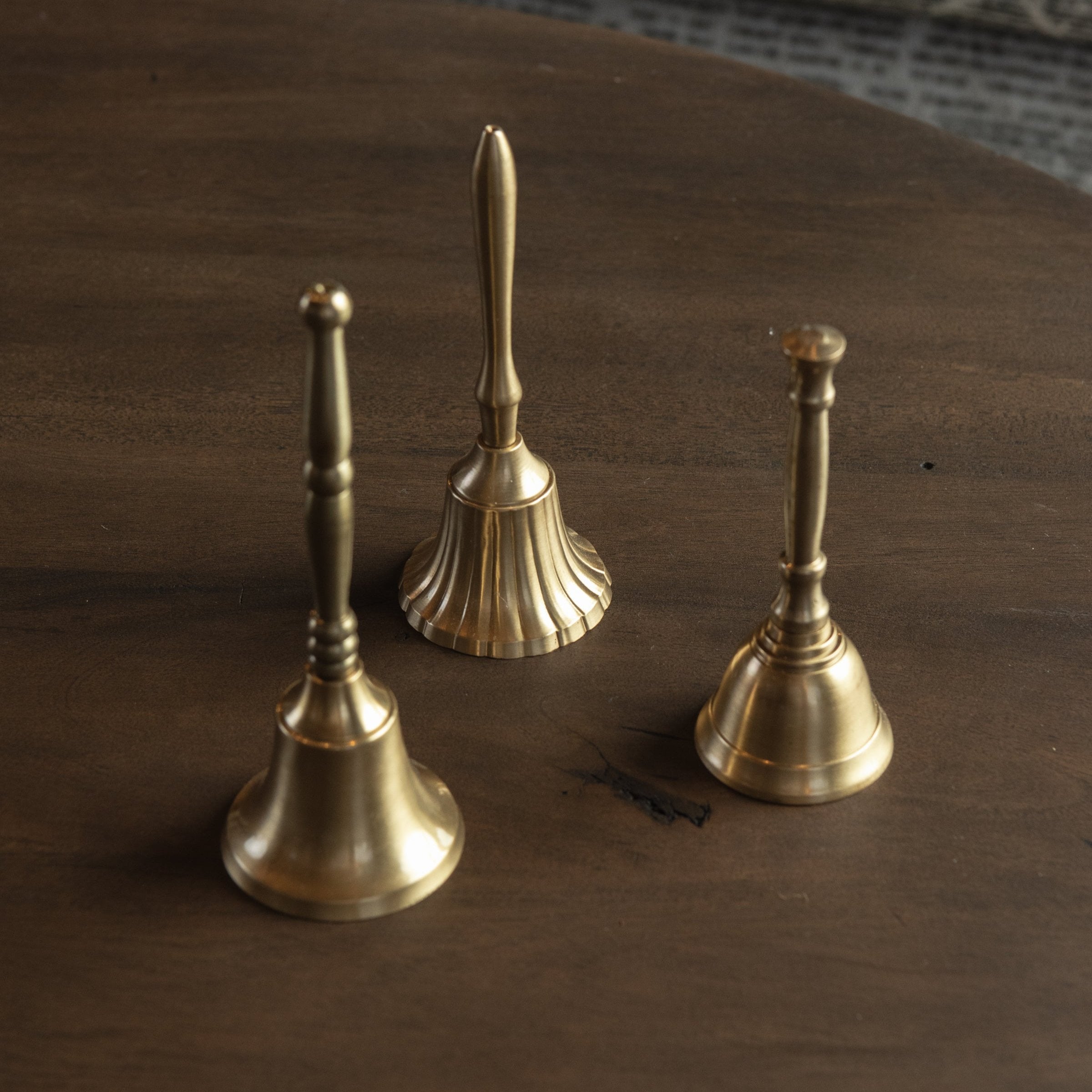 Set of three Decorative Bell on a dark wood table at Addison West