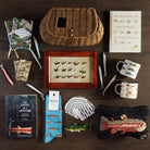 collection of gifts for the angler including vintage trout flies framed print, fishing books, fish playin cards, fish hand hooked wool pillow, fish socks at Addison West