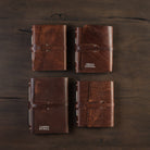 Four leather bound handmade  made in Vermont journals on a dark wood table at Addison West