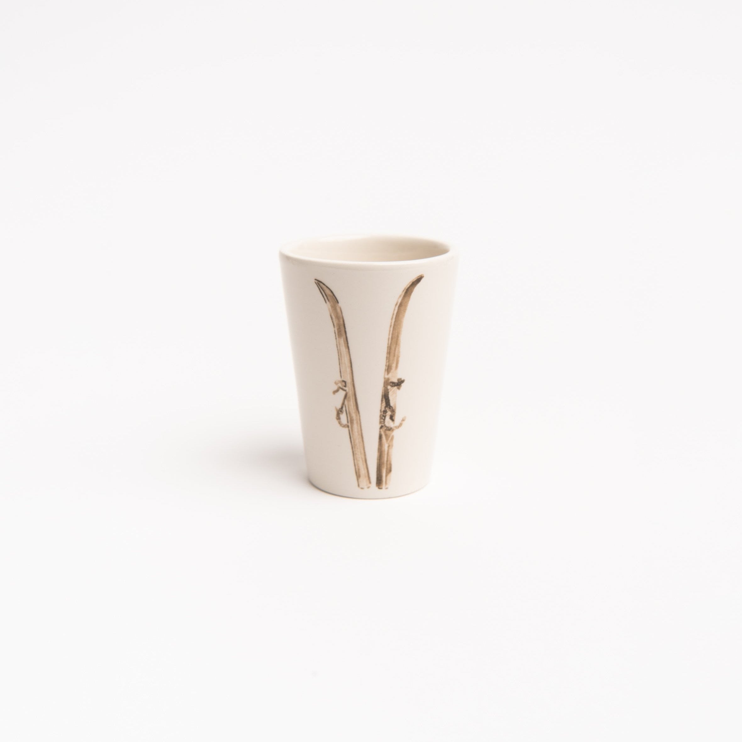 Espresso cup with set of skis on front on a white background