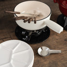 Swissmar Lugano 9 Piece Cast Iron Fondue Set - White on a wood table at Addison West and Vintage Fondue Plates