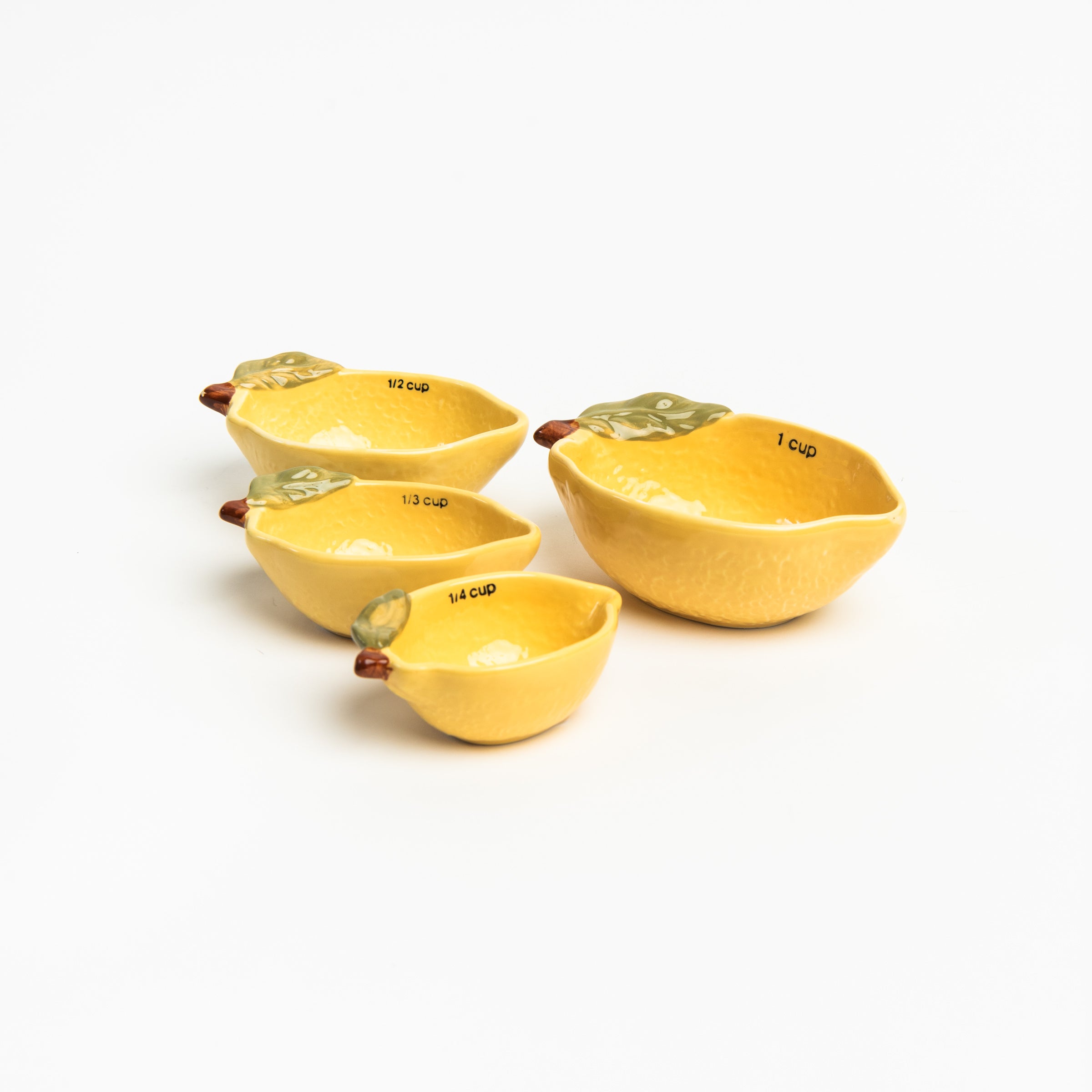 Set of 4 yellow lemon shaped stoneware measuring cups on a white background