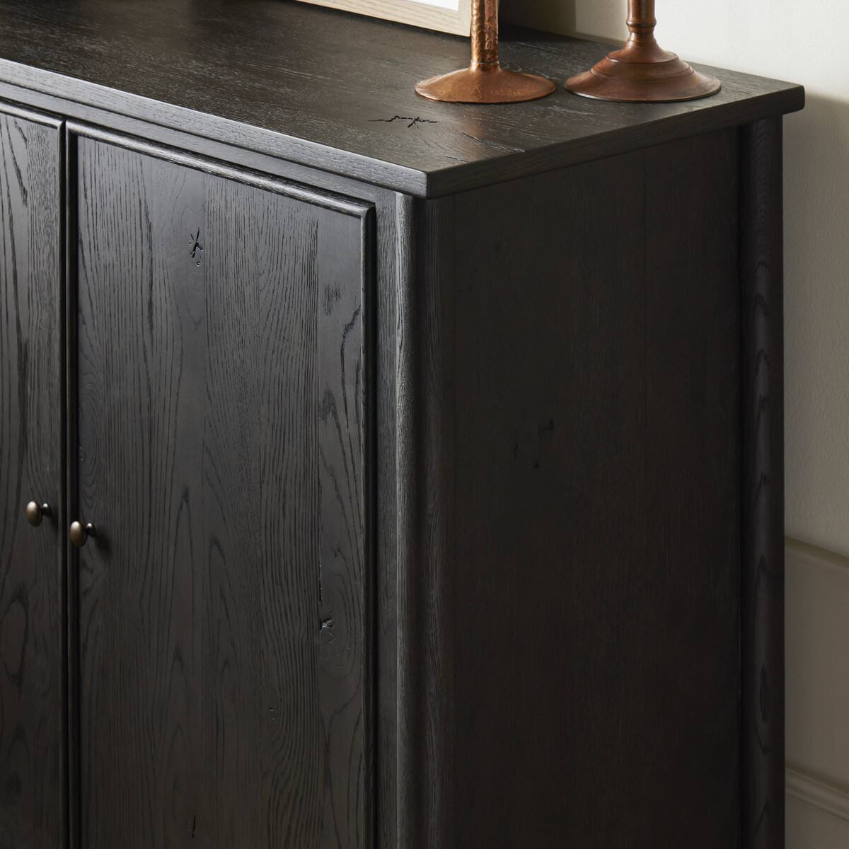 Close up of Amber Lewis x Four Hands Bari Bar Cabinet in Cracked Smoked Black Veneer in a neutral room at Addison West