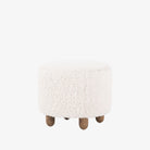 Four hands brand Aniston ottoman in natural shearling style upholstery on a white background