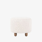 Four hands brand Aniston ottoman in natural shearling style upholstery on a white background