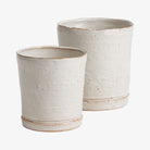 Set of two Asher pots by Napa home with cream finish and integrated saucer on a white background