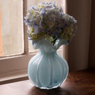 Beatriz Ball Medium Vento Bud Vase in Sky on a wood table in front of a window at Addison West