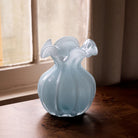 Beatriz Ball Medium Vento Bud Vase in Sky on a wood table in front of a window at Addison West