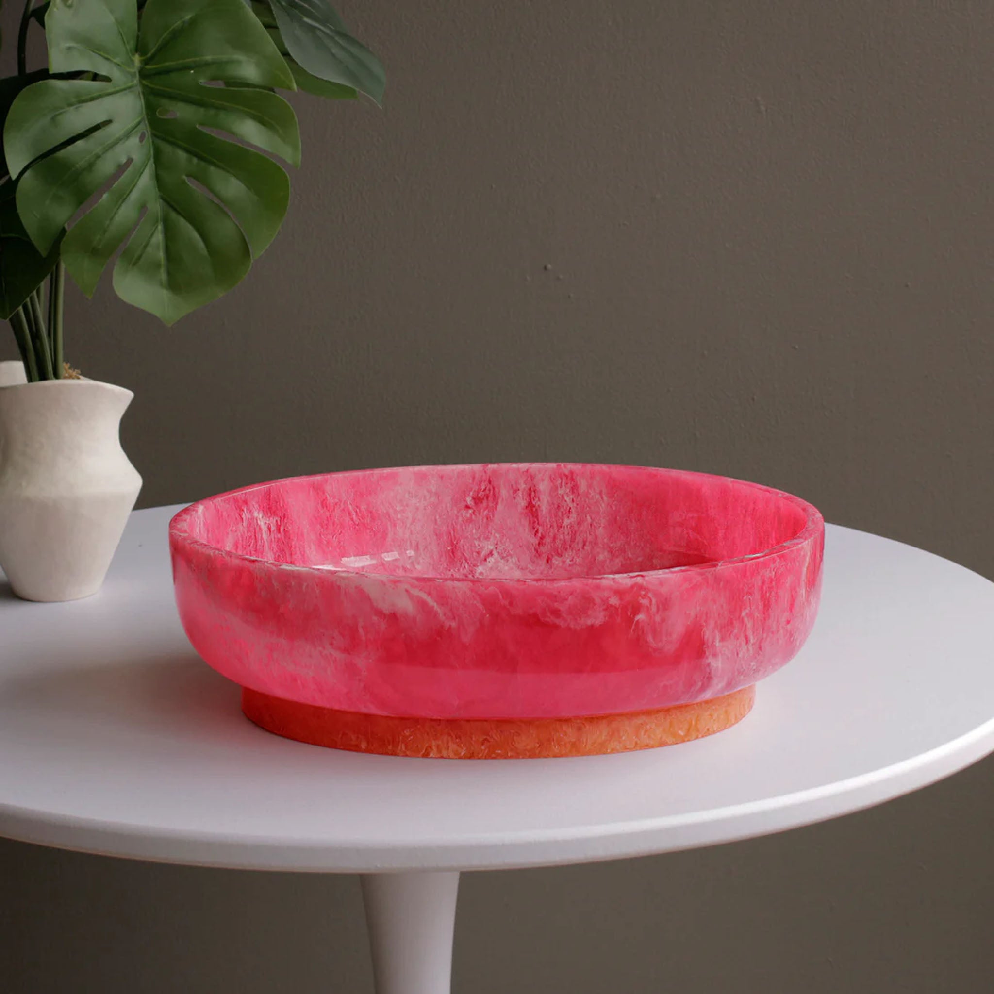 Beatriz Ball RESIN Rio Large Oval Bowl with Base in Pink & Orange on a white table at Addison West