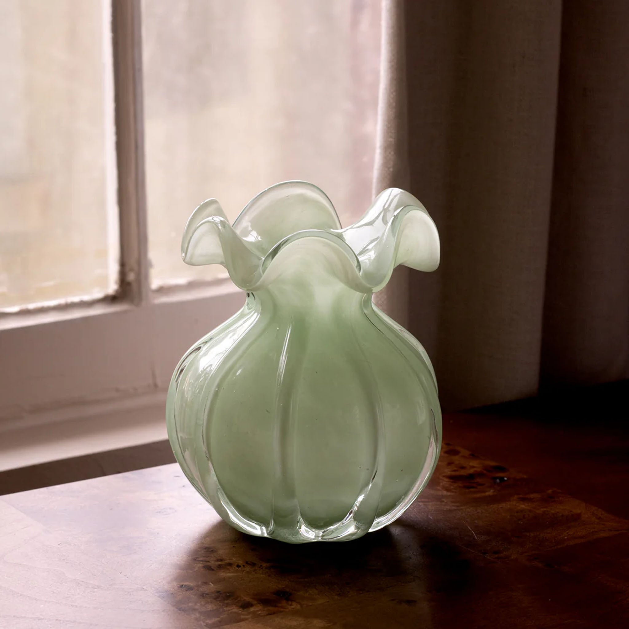 Beatriz Ball Small Vento Bud Vase in Jade on a wood table in front of a window at Addison West