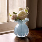 Beatriz Ball Small Vento Bud Vase in Sky on a wood table in front of a window at Addison West