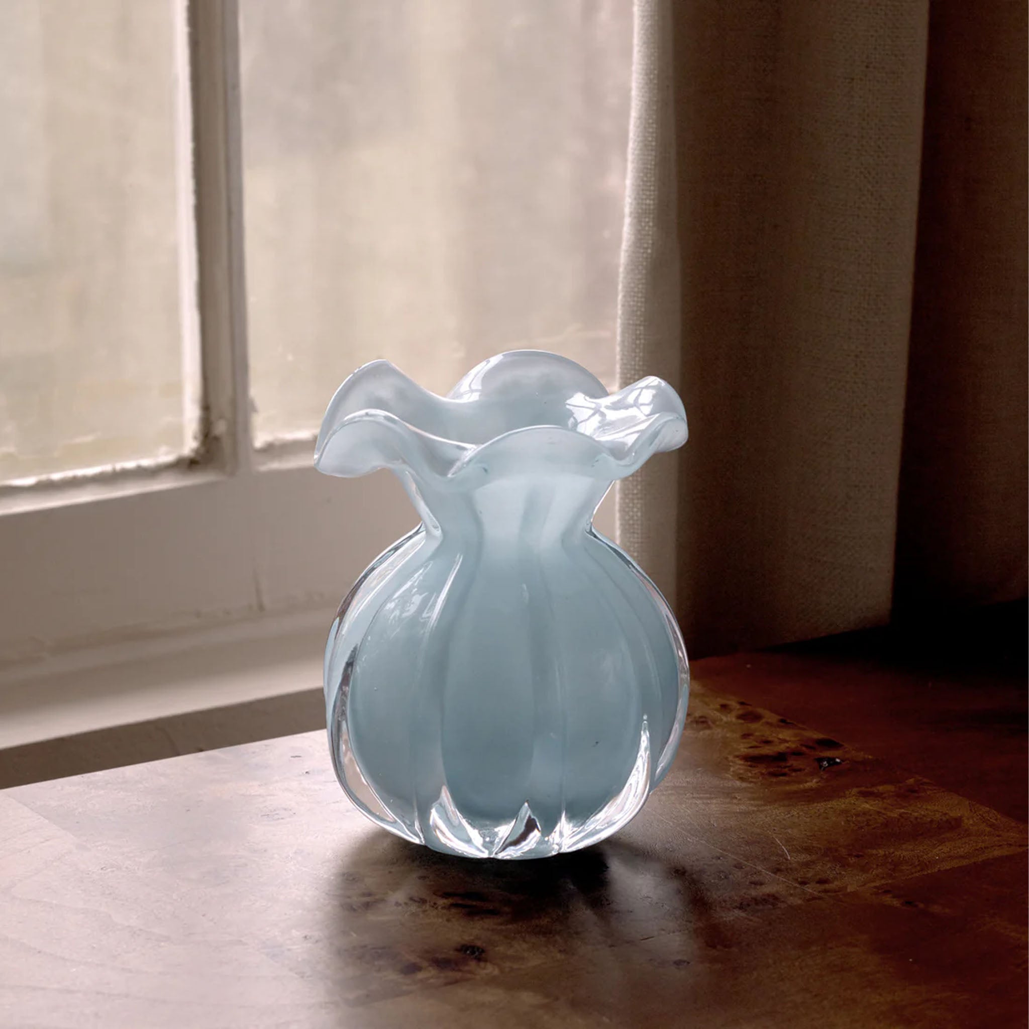 Beatriz Ball Small Vento Bud Vase in Sky on a wood table in front of a window at Addison West