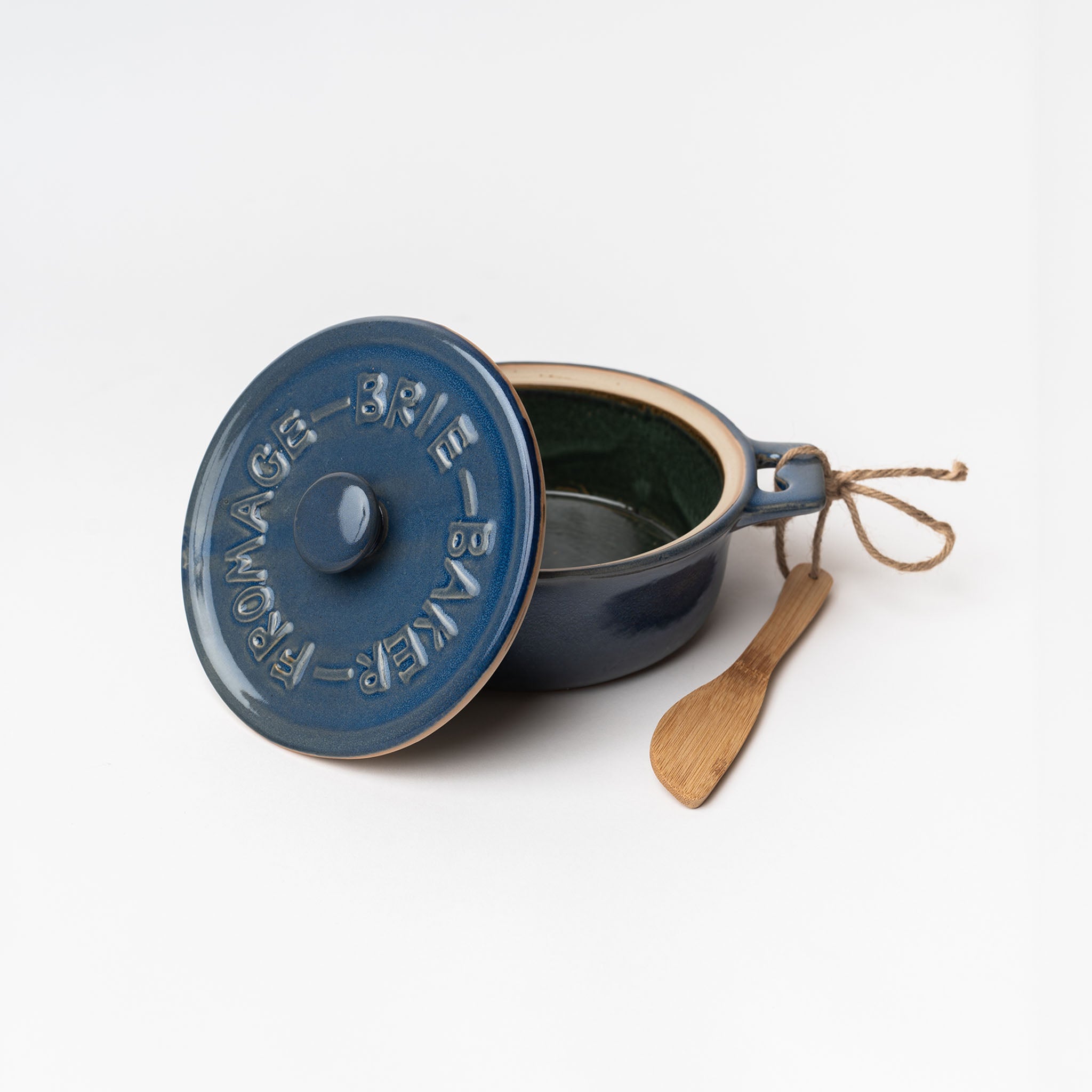 Blue brie baker with bamboo spreader on a white background