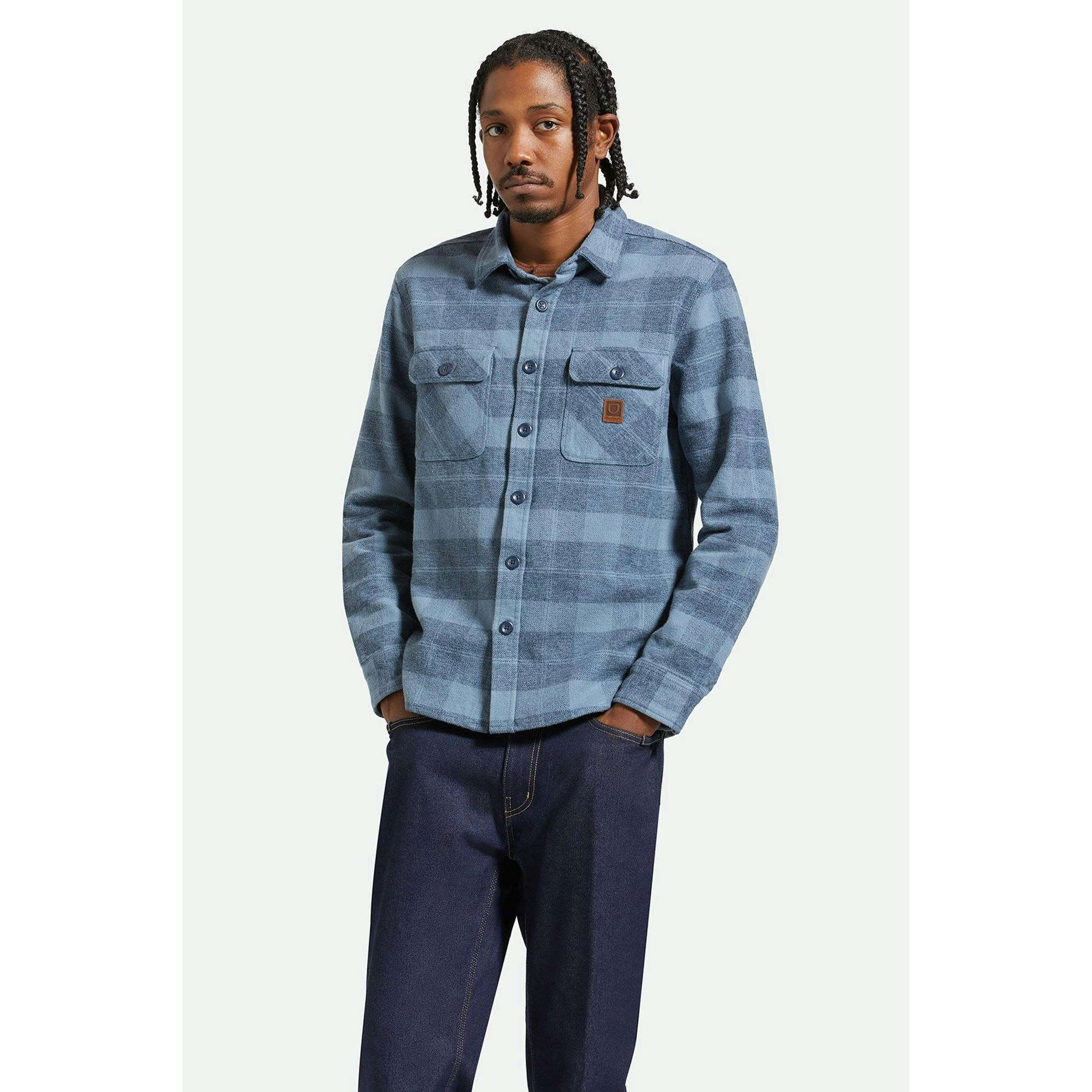 Model wearing Brixton Bowery Men's Heavyweight Flannel in Mirage Blue  with dark wash jeans on a white background