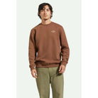 Model wearing Brixton Men's Parson Patch Crew in Pinecone Brown with olive pants on a white background