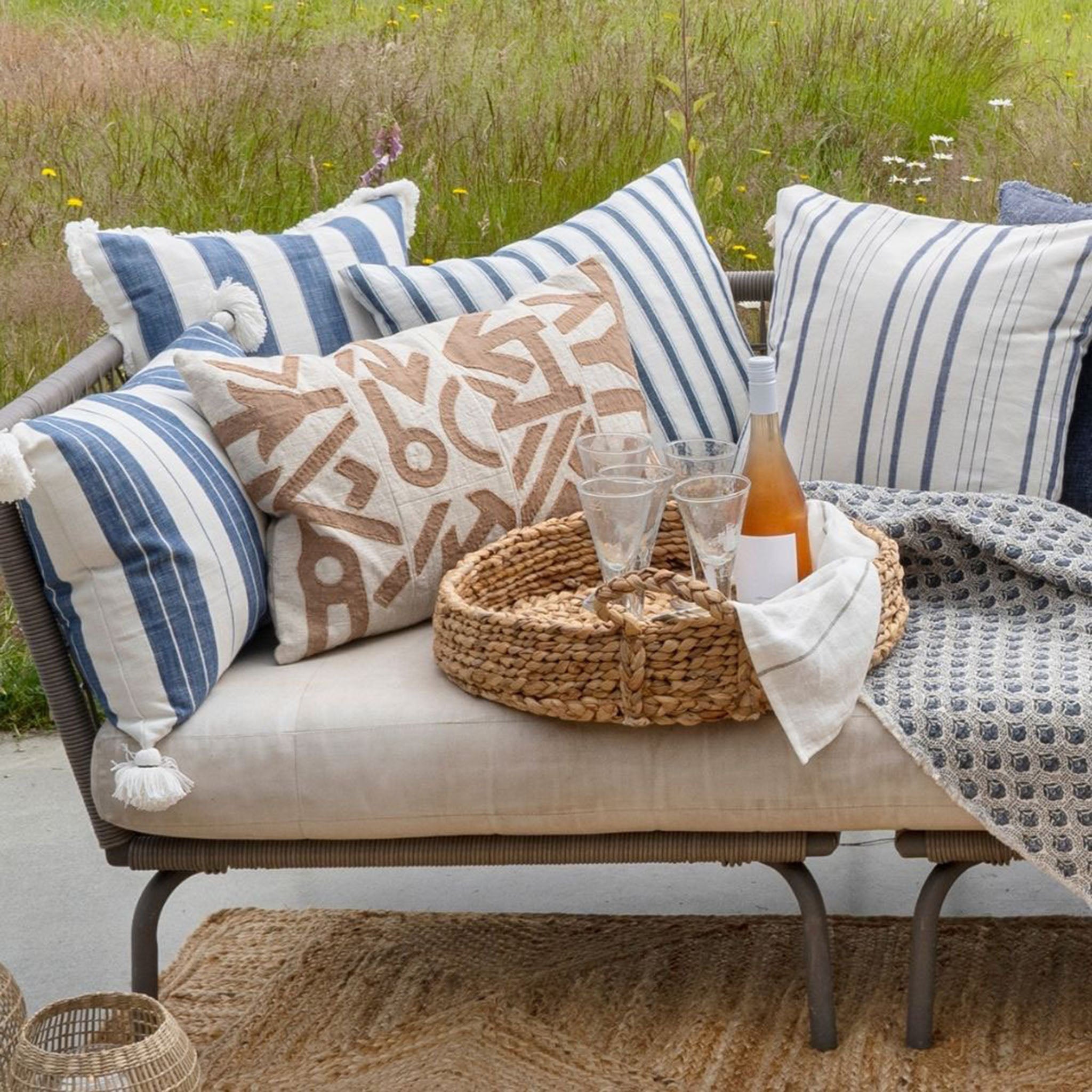 Outdoor pillows on sofa near long grasses